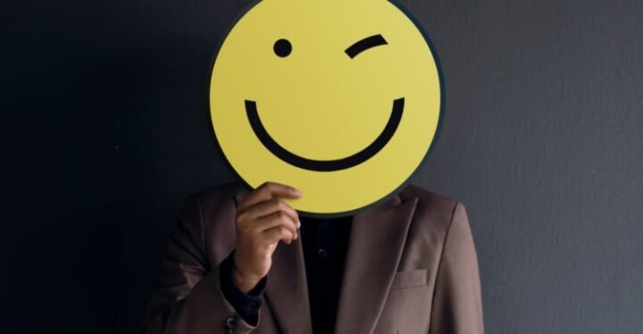 Bild von Mann der ein Zwinker Emoji vor sein Gesicht haltet.